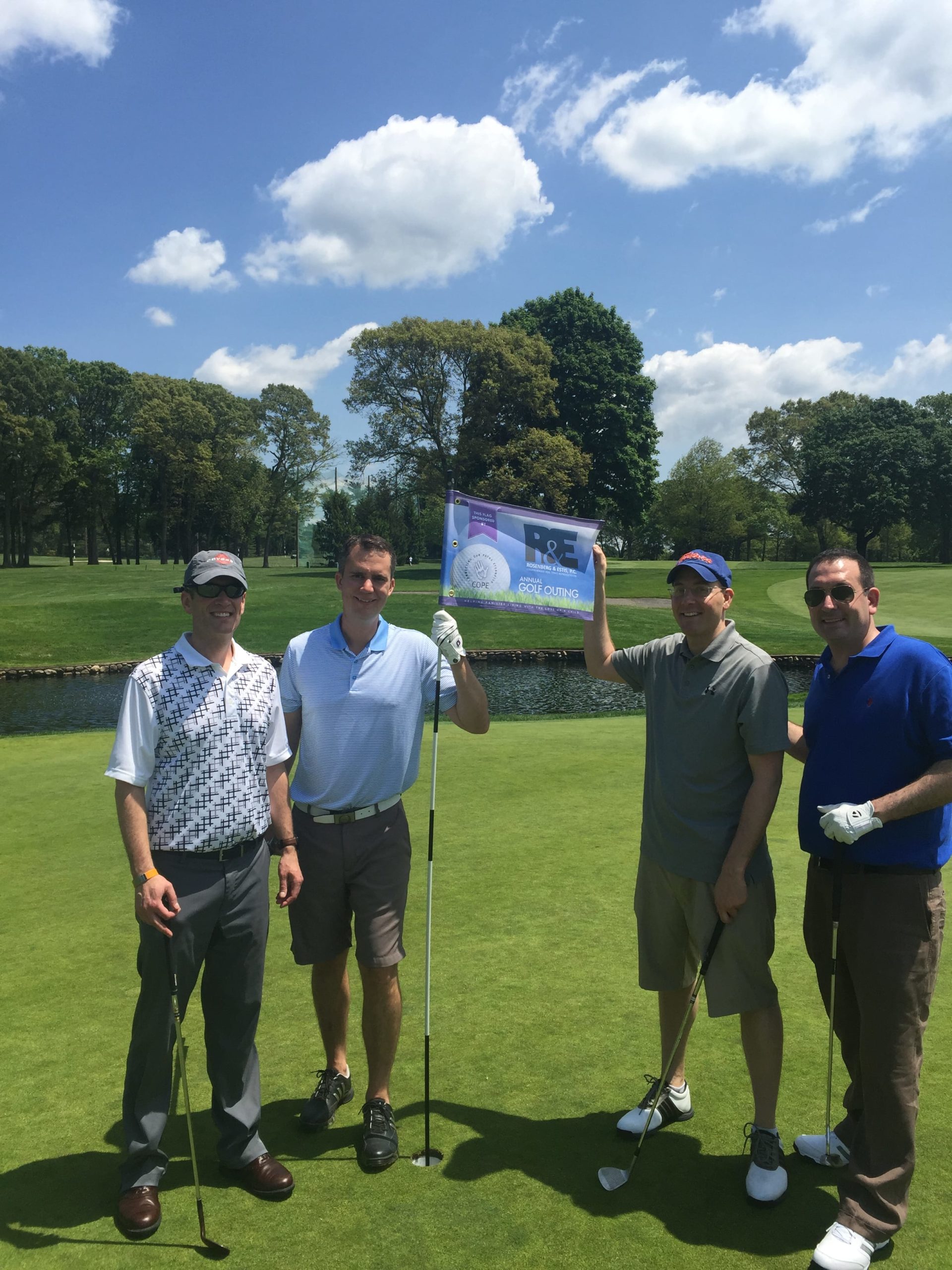 Photo of the R&E's participants holding the flag Rosenberg & Estis, P.C. comprehensive Real Estate Representation Annual Golf Outing | Connecting Our Paths Eternally